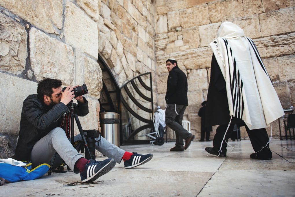 Man sitting by a temple while taking journalistic photographs
