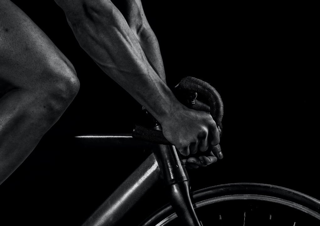 black and white photo of a cyclists arms and leg.