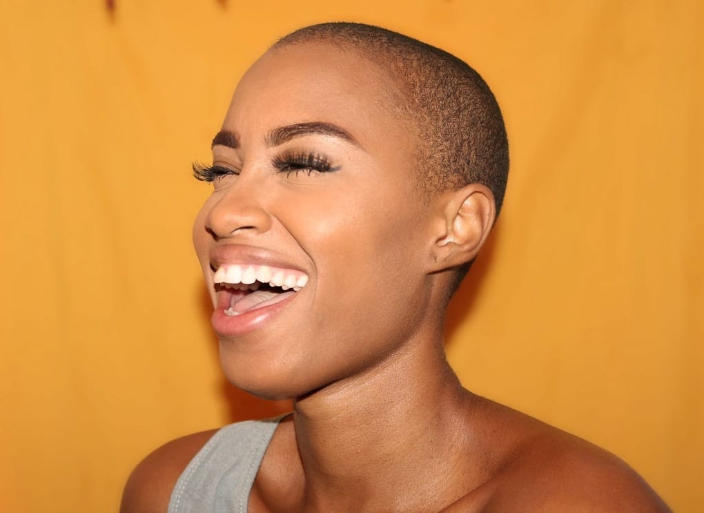 A woman confidently smiling and laughing with a nice orange background