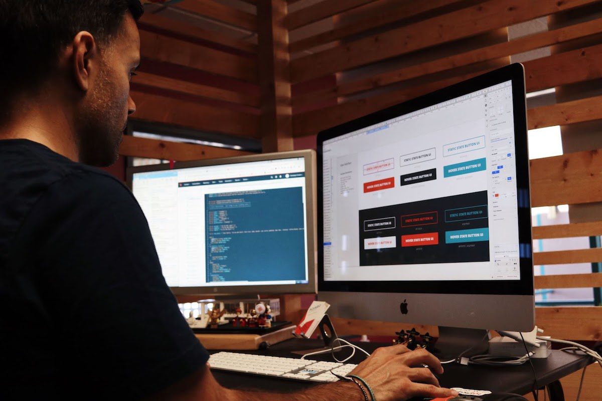 A web developer working in front of two computer monitors.