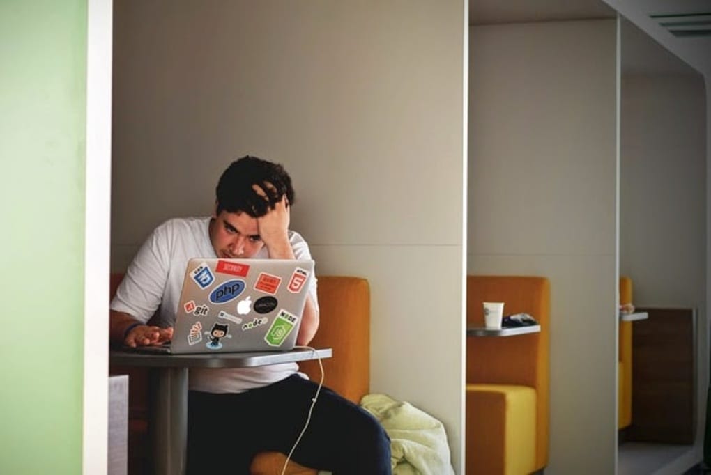 Man sitting at a coffee shop fully focused on his laptop.