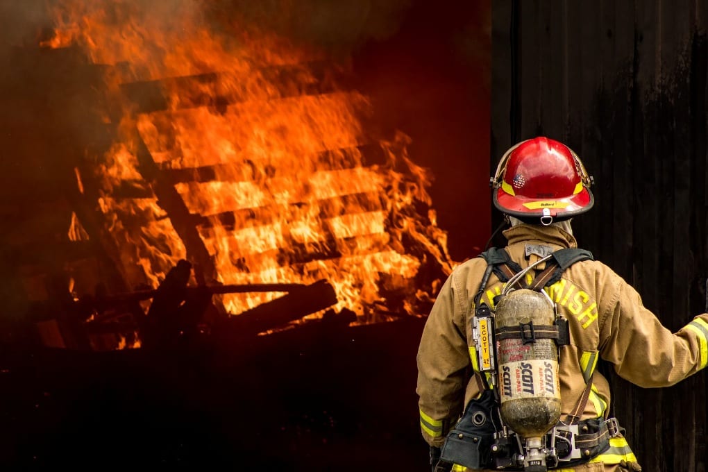 a firefighter standing in front of a wall of flames