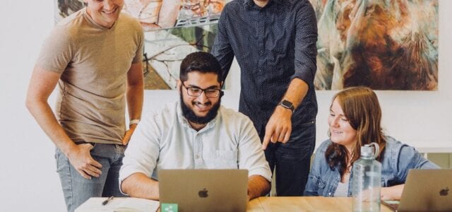 four-people-looking-and-smiling-at-computer-screen