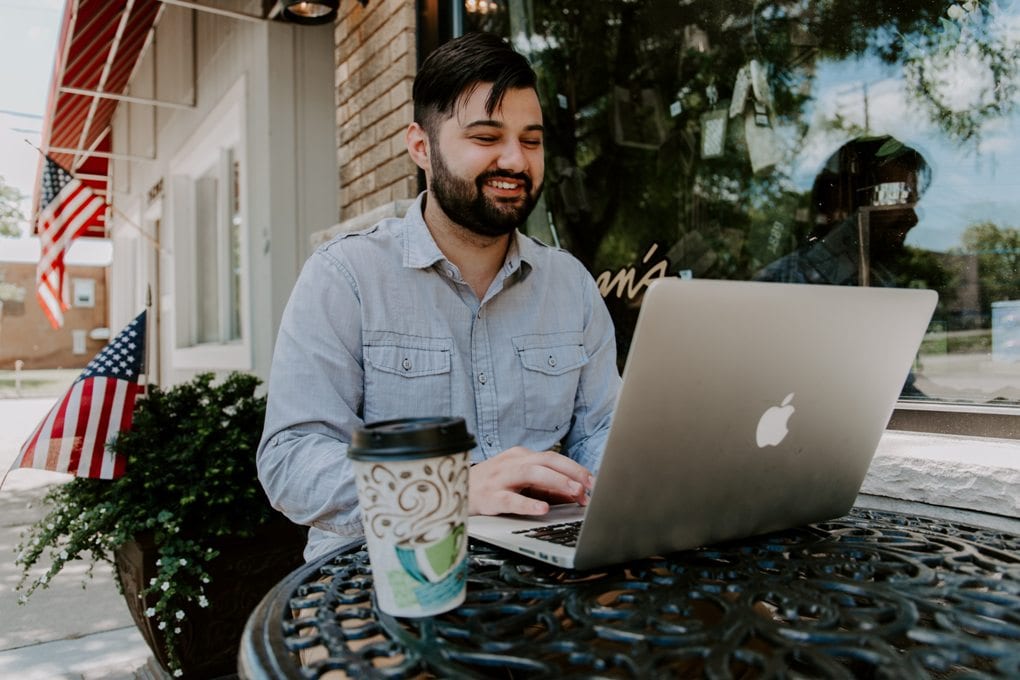 Man in denim at outside cafe table with laptop