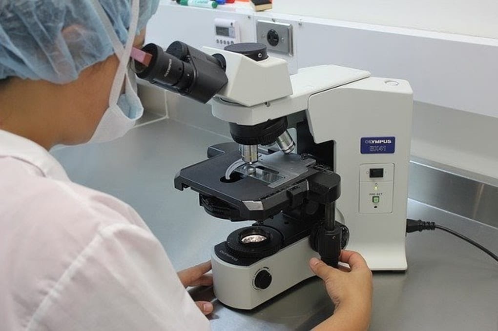 A female scientist looking through a microscope.