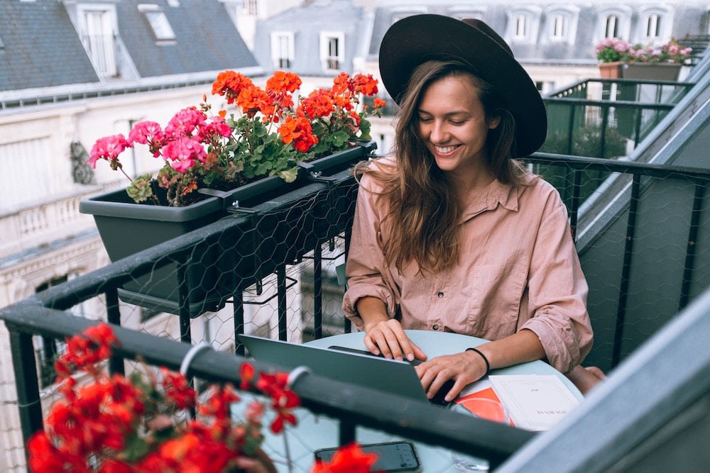 A woman sitting on her balcony working on a freelance data entry project.