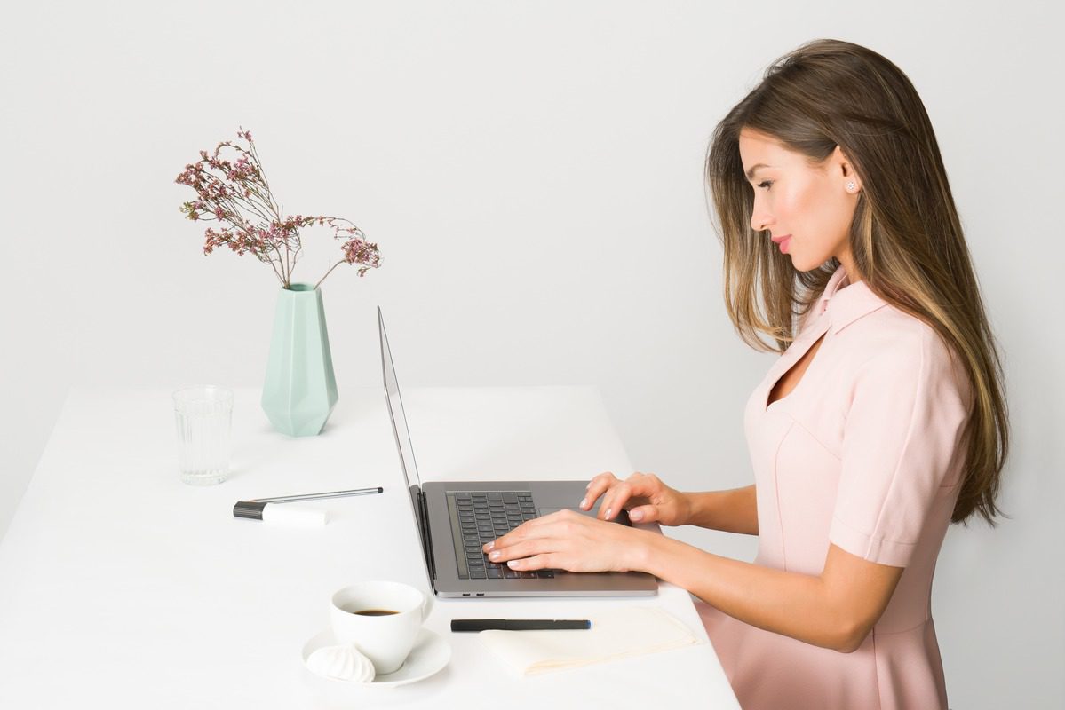 A women dressed in pink learning HTML on a laptop.