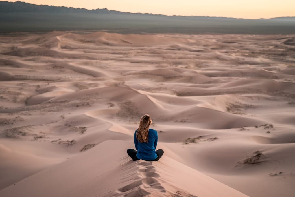 Woman sitting on the sand dunes. 