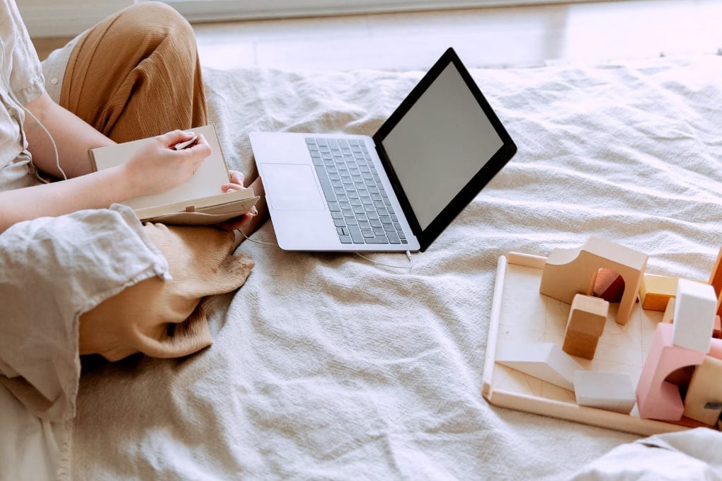 women using a laptop on a bed