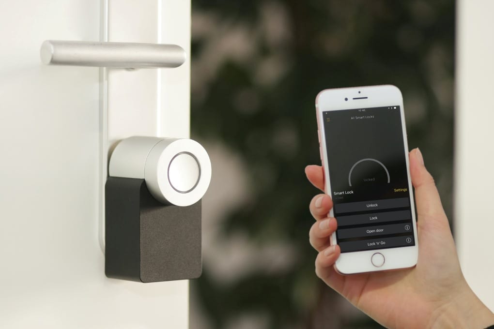 Person holding smartphone next to smart lock on front door