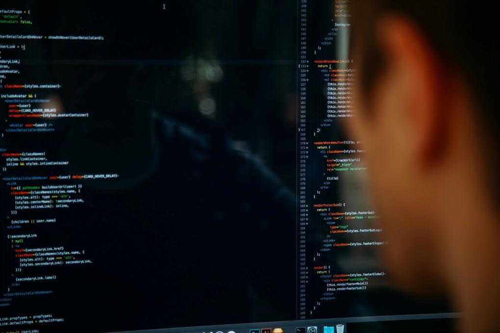 Person staring a black computer monitor displaying colorful code