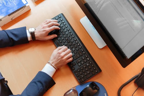 A picture shows two hands typing on a black keyboard in front of a computer screen.