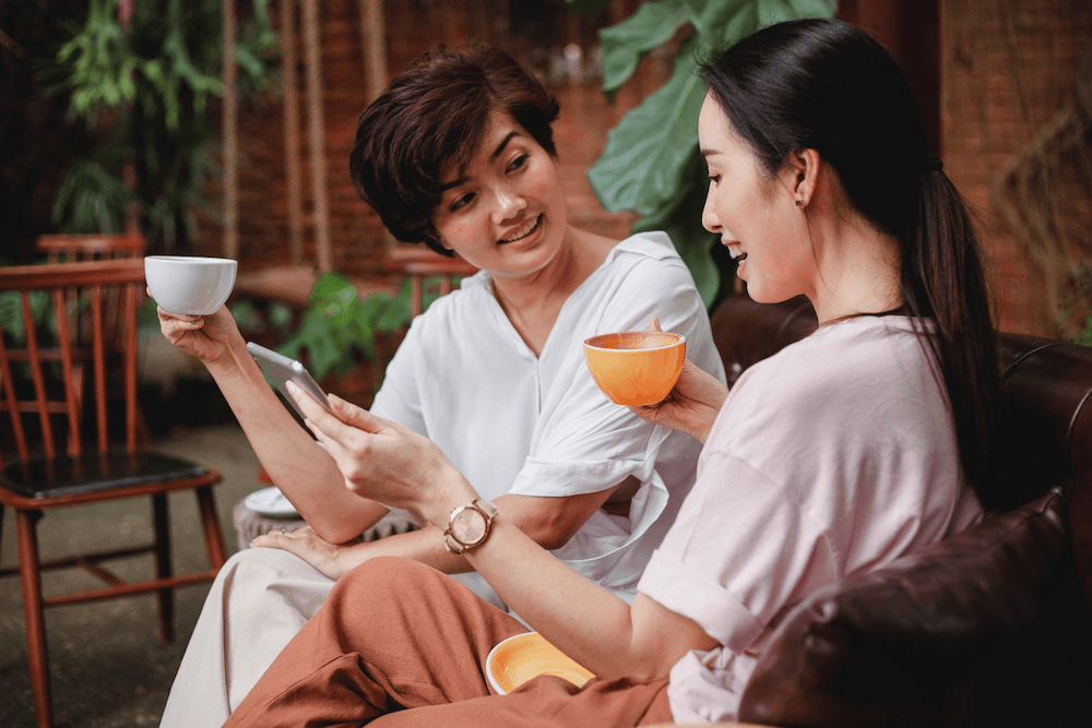 wo women drinking tea and looking at a tablet