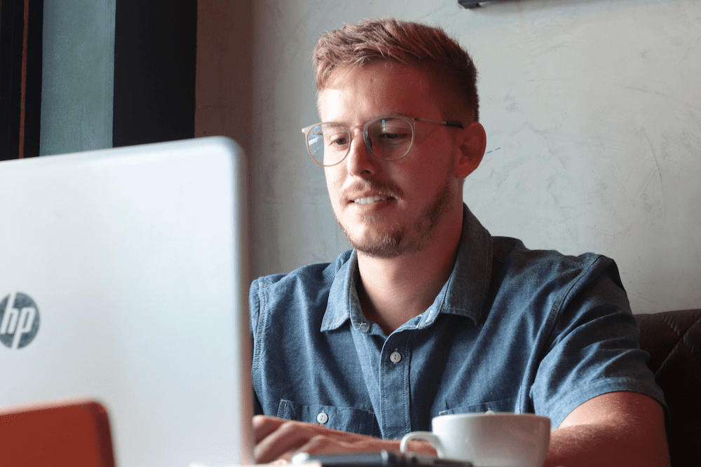 smiling man typing on an HP laptop computer