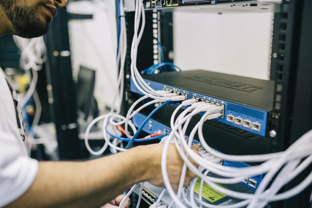  man holding connection cables inside a server room