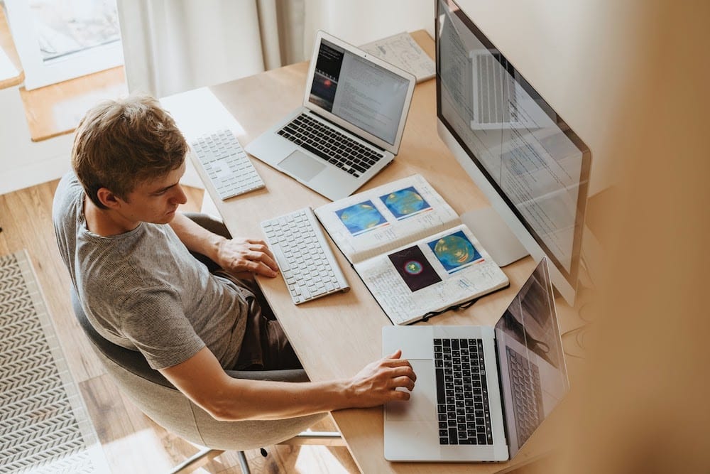 A man working on three computers.