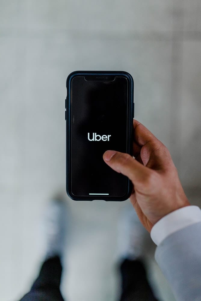 A person holding a black phone with the word Uber written on it.