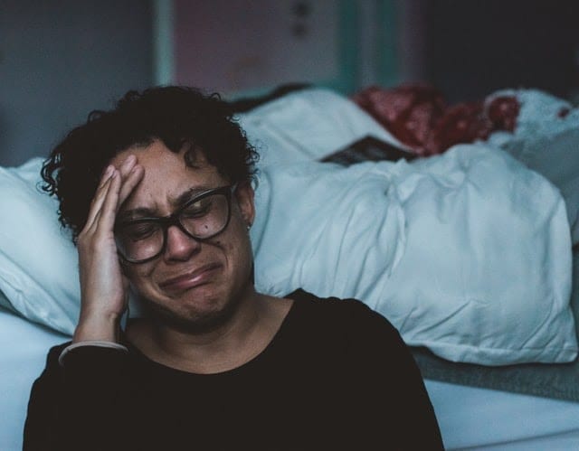  A person crying beside a bed