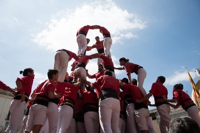 Group of people dressed in red and white making a human pyramid 