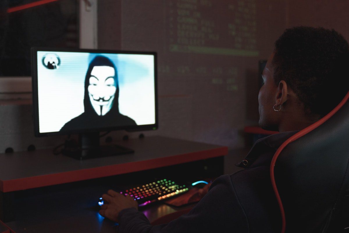 Person looking at a hacker on a computer screen How to Become a Cyber Security Analyst