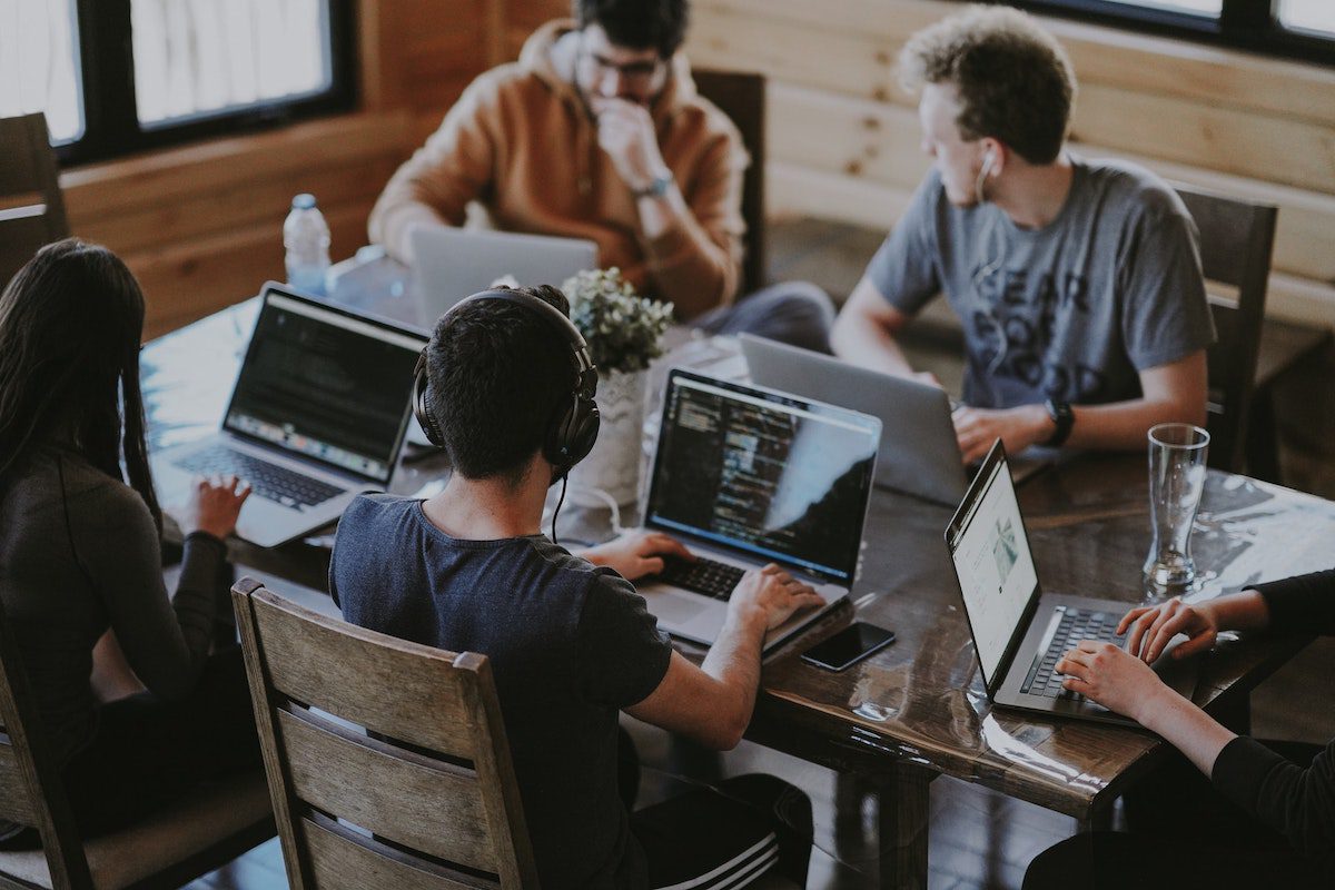 A group of people sat around a table working on laptops. How to Become a Full Stack Developer