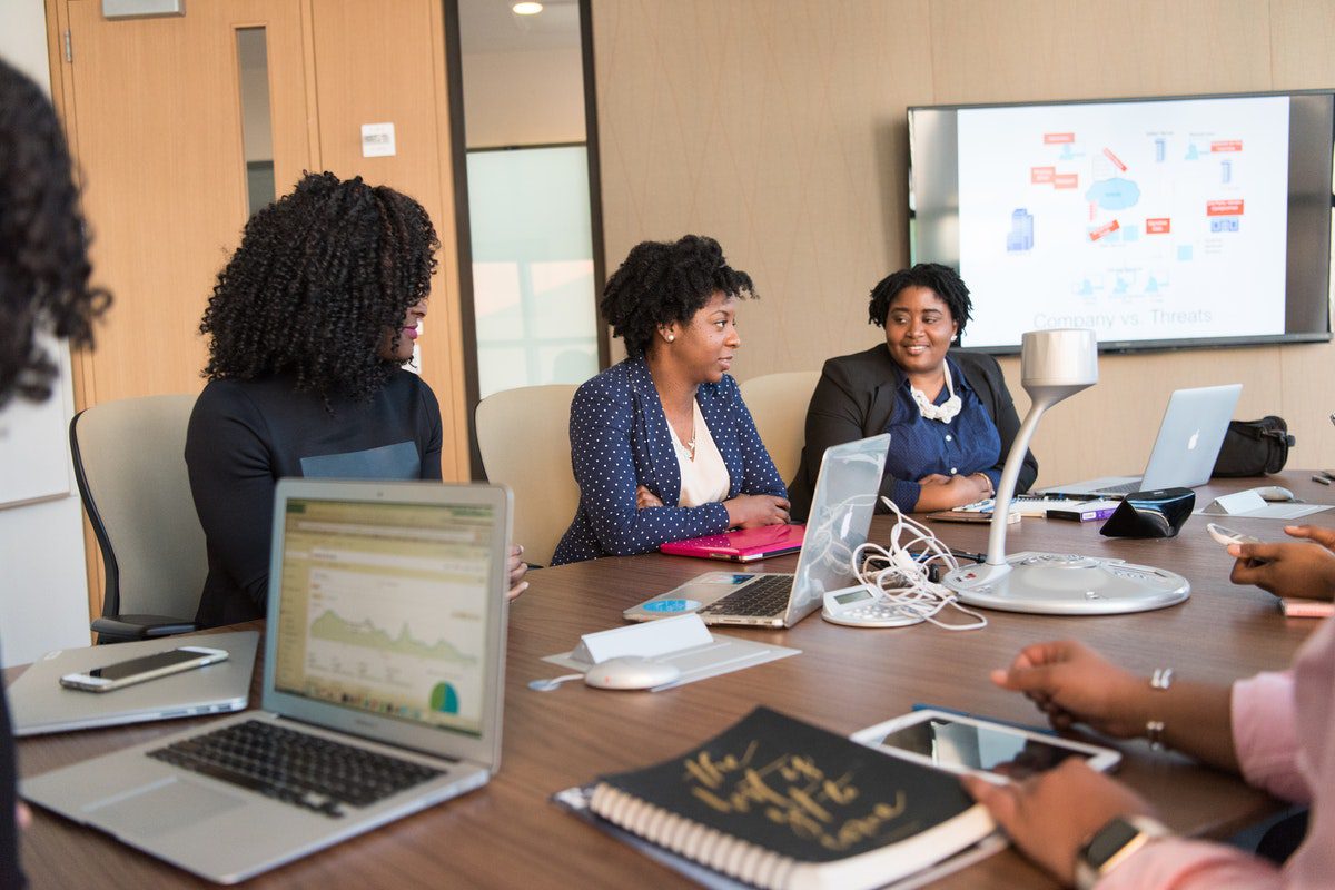 Woman sitting around a big table with laptops and notebooks How to Become an Information Systems Analyst