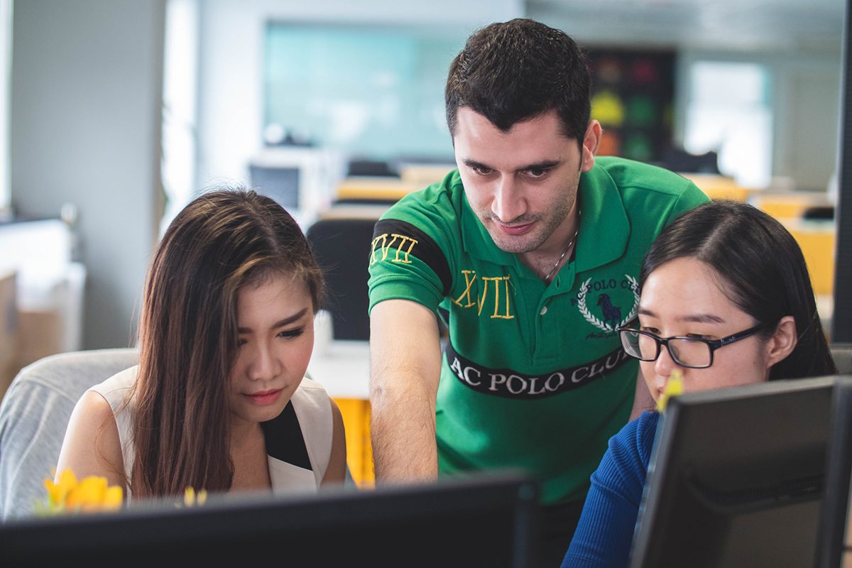 Two women and a man at a desk looking at a computer How to Apply for an Apprenticeship