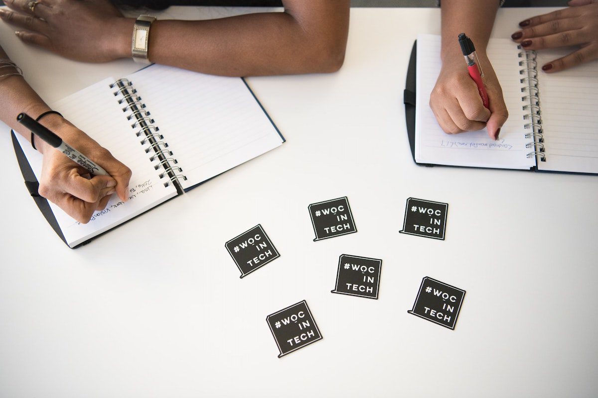 two women writing on notepads How to Become a Salesforce Developer