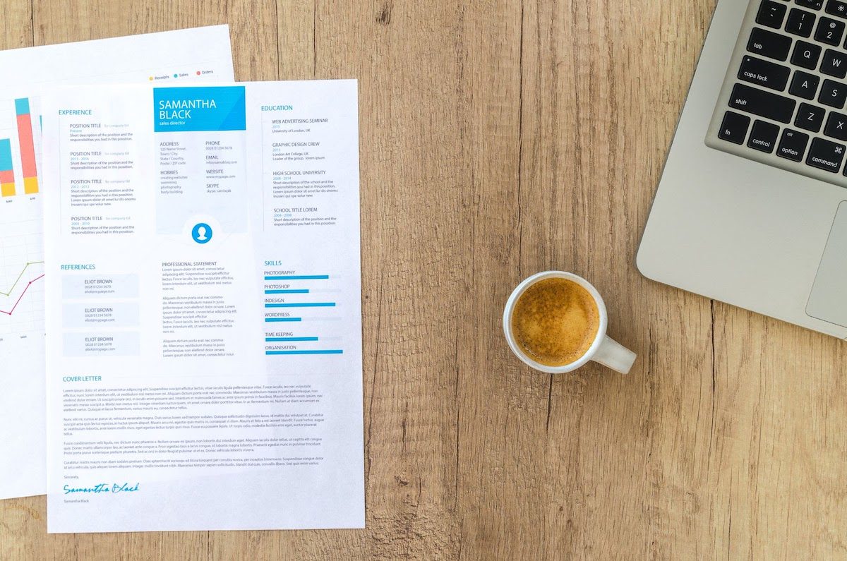 A small coffee cup on a brown table next to a laptop computer and some papers with graphs how to become a data mining specialist