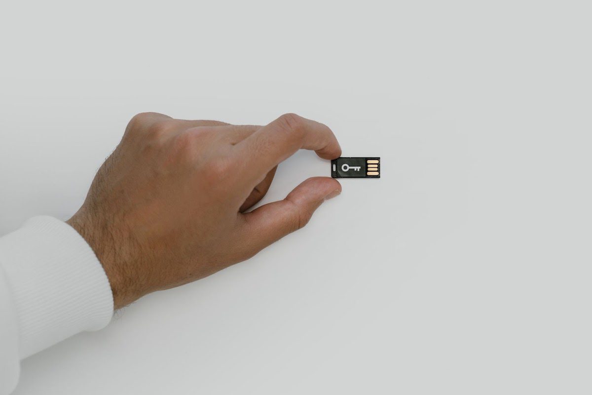 Man holding a USB flash drive with the picture of a key network security analyst