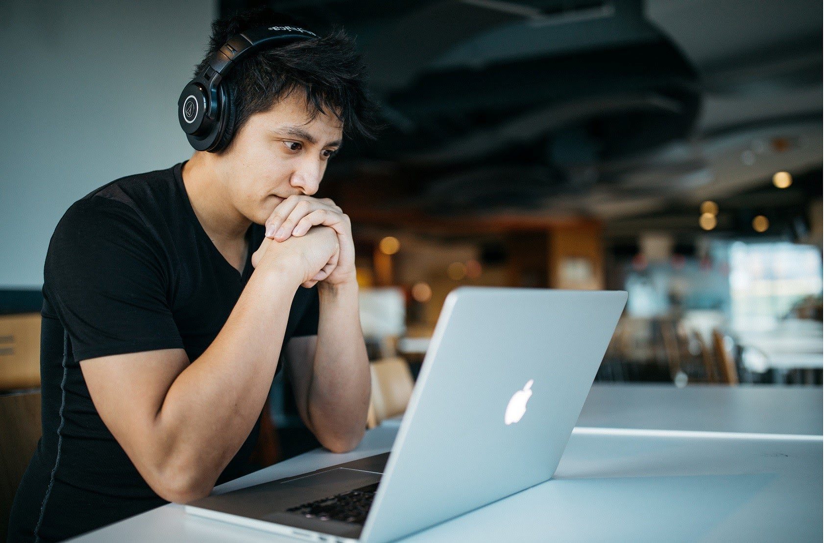  Man wearing headphones looking at a MacBook How To Find An Apprenticeship 
