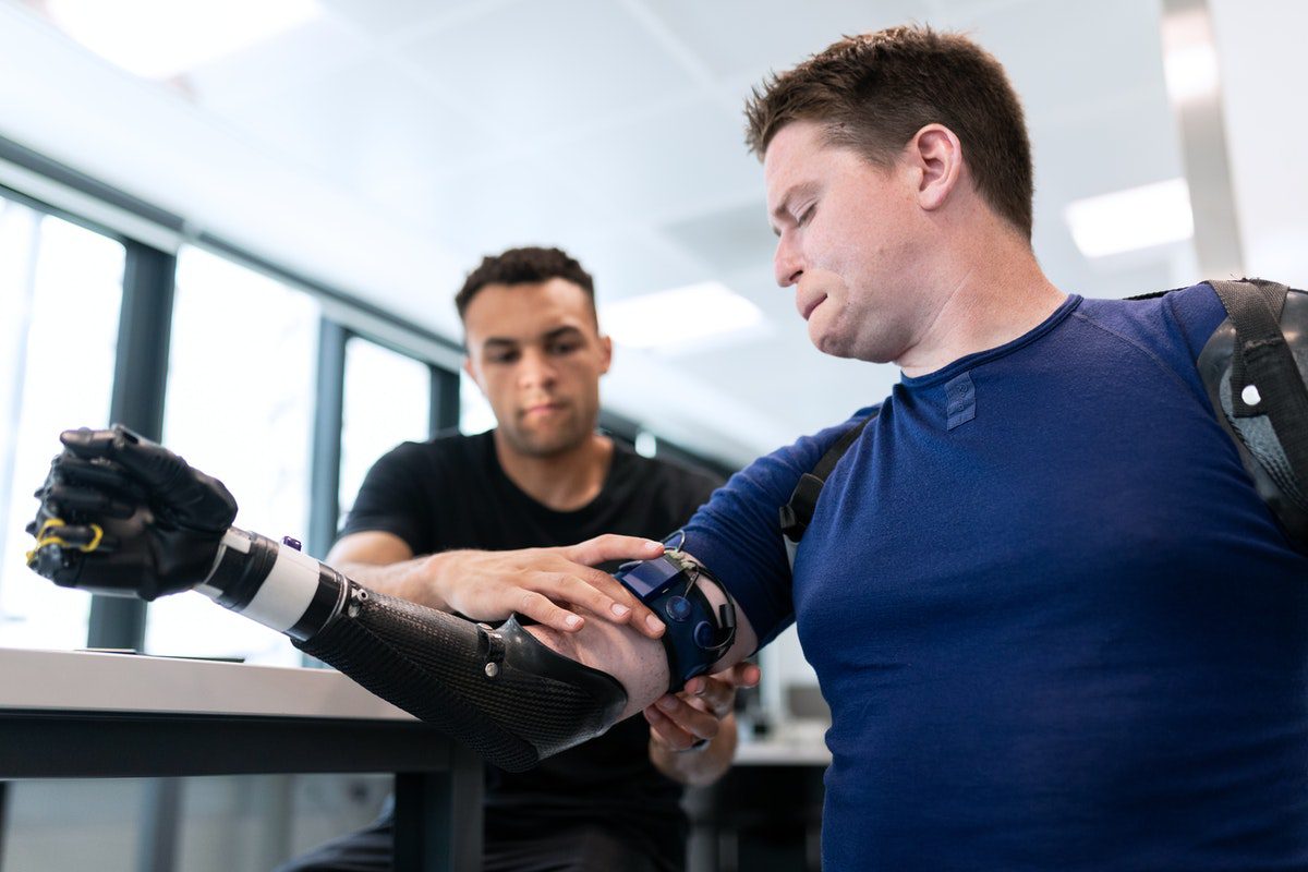 An engineer fitting a prosthetic arm on a male patient how to become a robotics engineer
