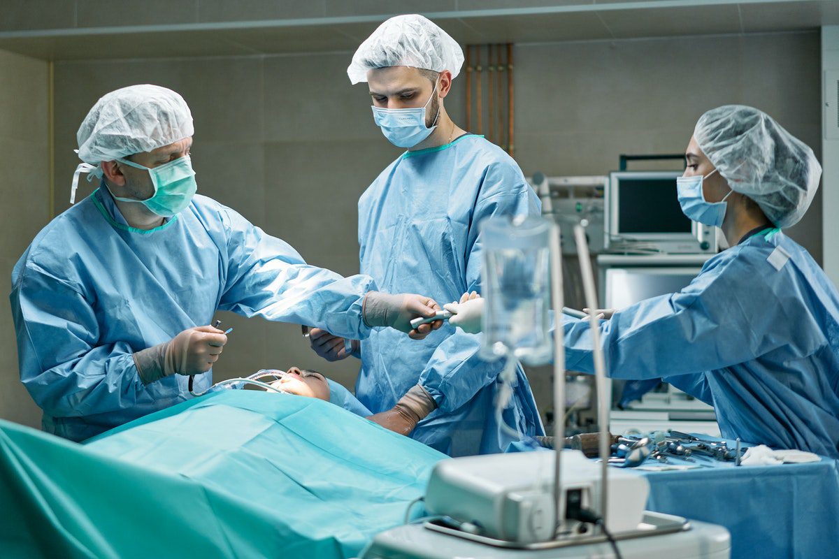 A doctor and two assistants perform a procedure on a patient. Physician Assisting Master's Degrees