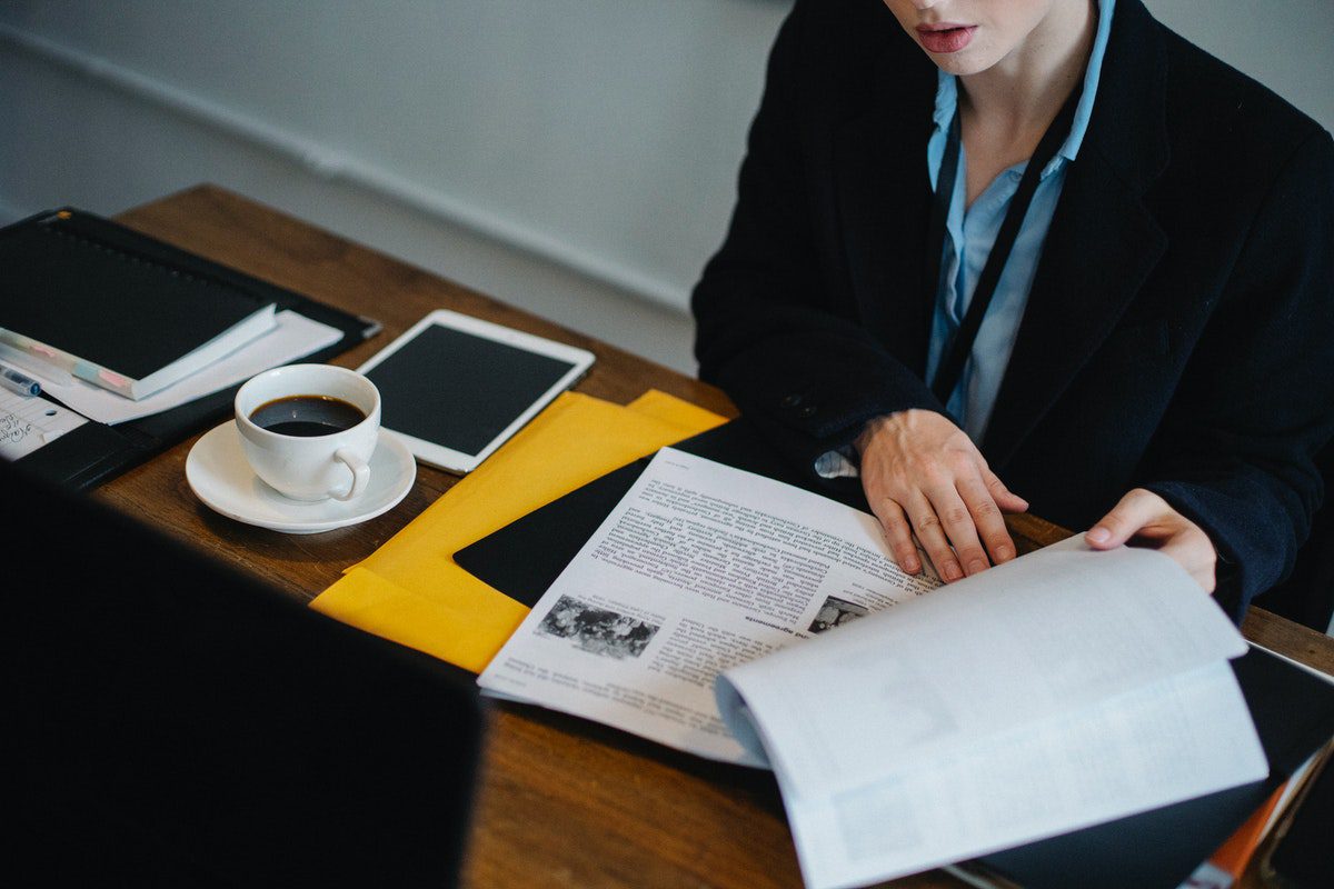 a woman drinking coffee while going through a business process analysis. Business Analyst Interview Questions and Answers