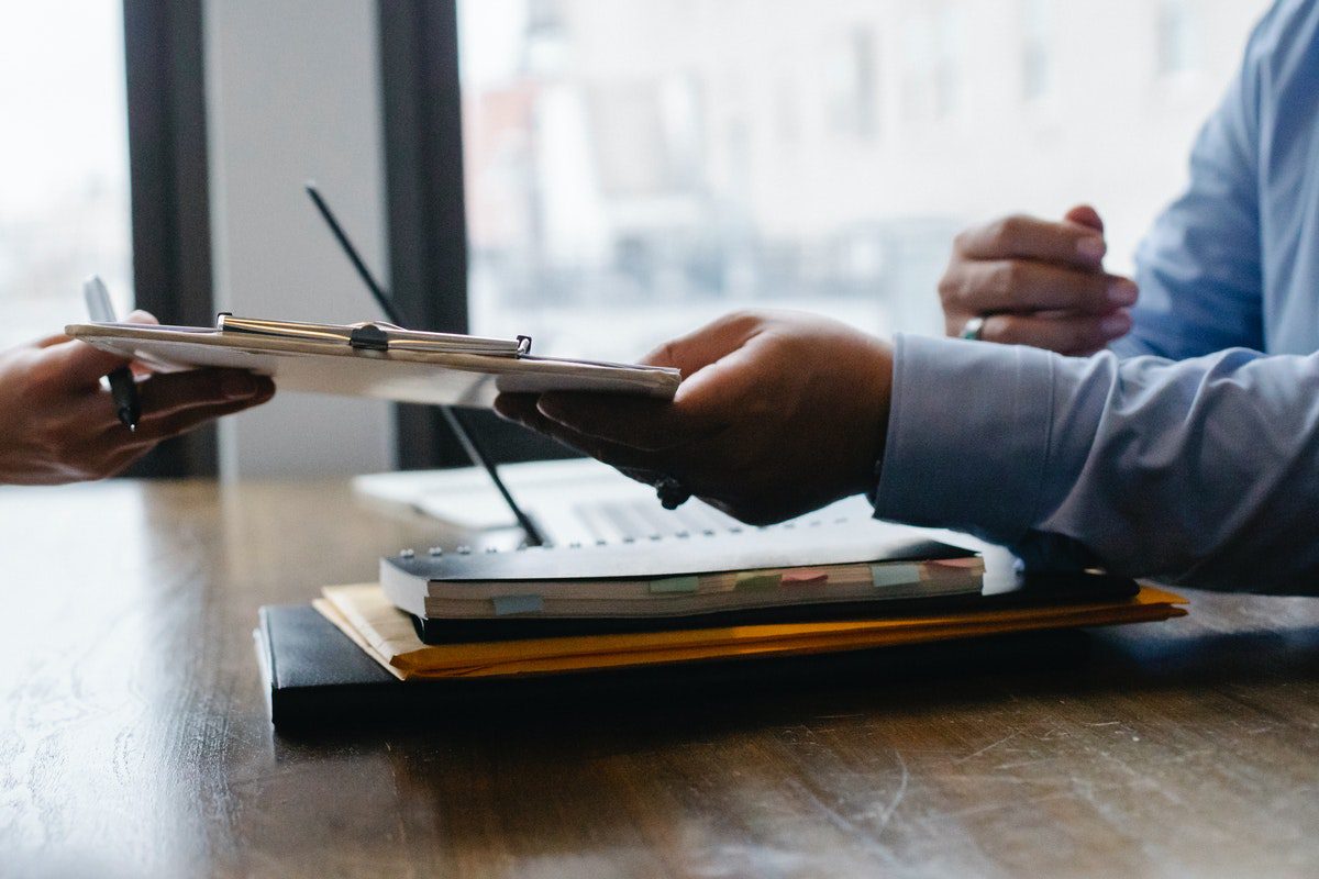 a woman handing over a clipboard to a man in a suit. Business Development Manager Interview Questions and Answers