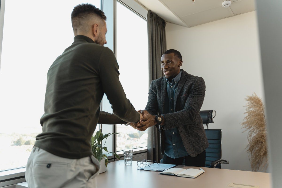 Two men shaking hands while standing up. Copywriter Interview Questions and Answers