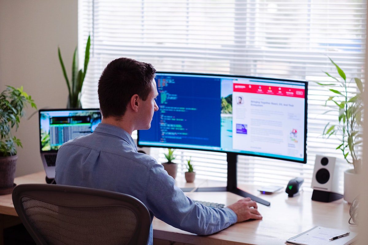 Man in grey shirt sitting in front of a desktop monitor. Director of Finance Interview Questions and Answers