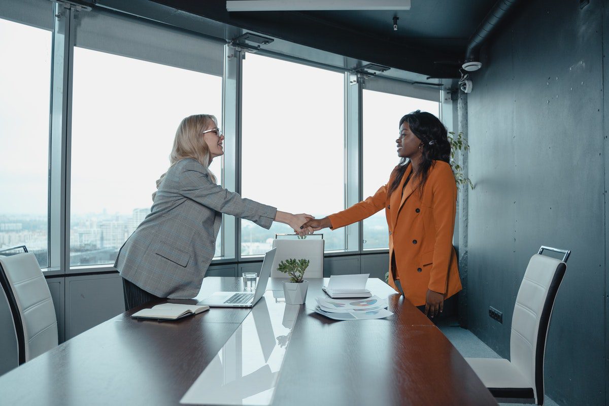 Women shaking hands across a conference table. Mechanical Engineer Interview Questions and Answers