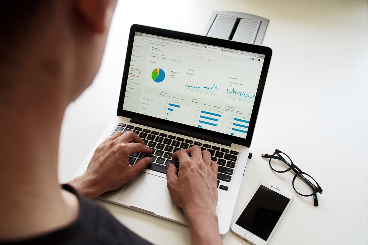 a man looking at a statistics report on his laptop with spectacles and mobile phone on the side. Sales Manager Interview Questions and Answers