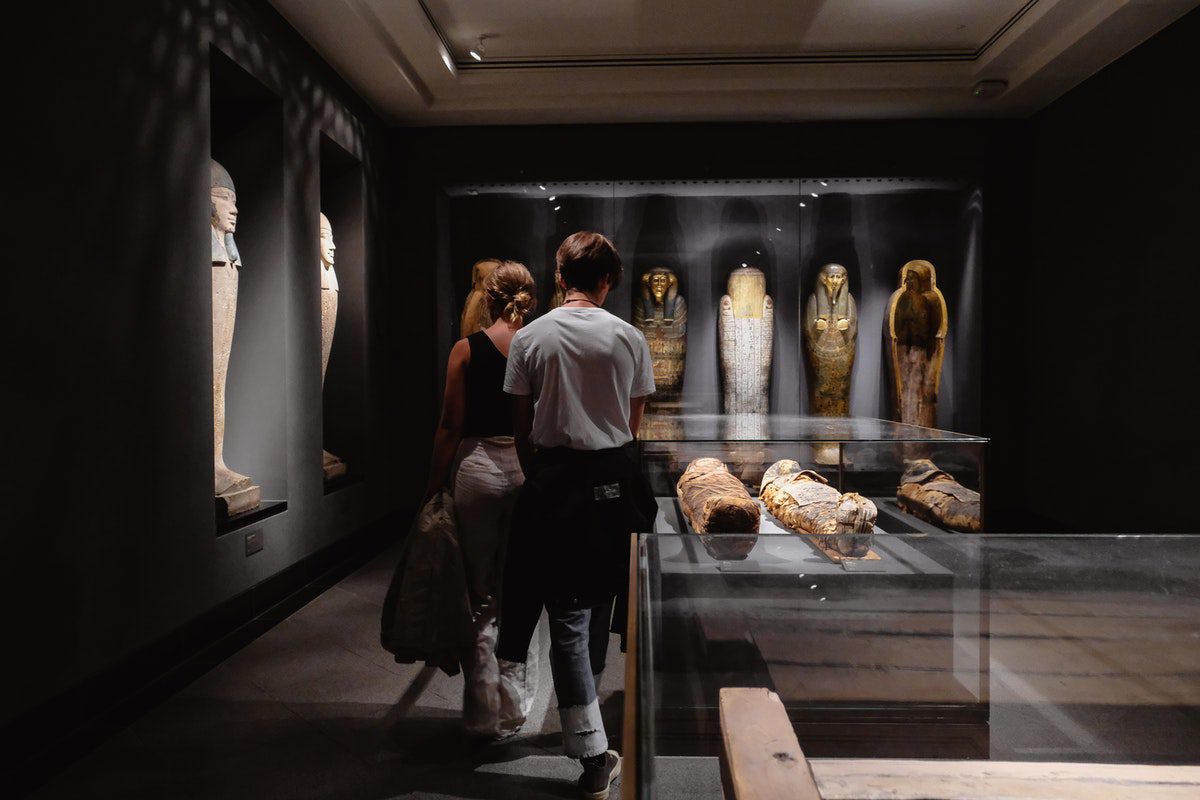 Two people are observing mummies and other historical artifacts inside a museum. jobs for history majors