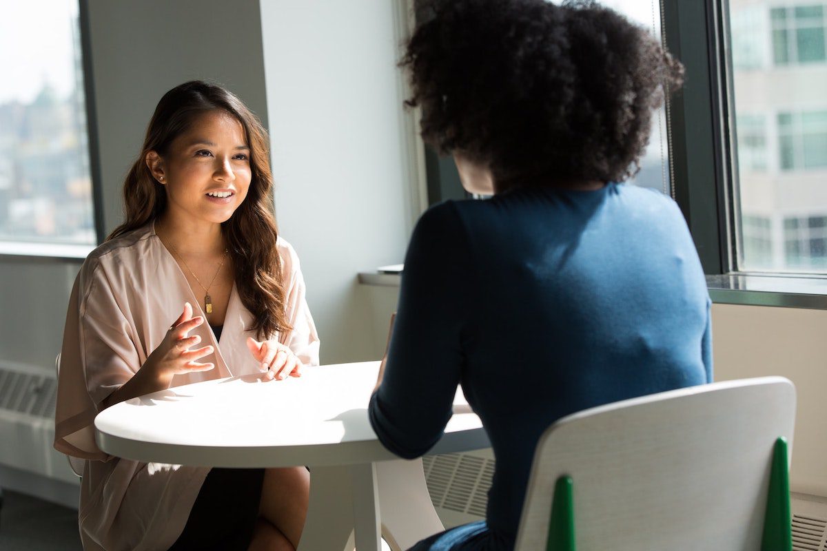 Two women talking at a table Network Administrator Interview Questions and Answers