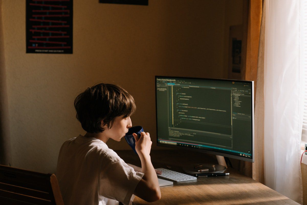 a kid drinking from a mug while sitting on a chair in front of a computer screen, which flashes lines of code SQL Interview Questions and Answers 