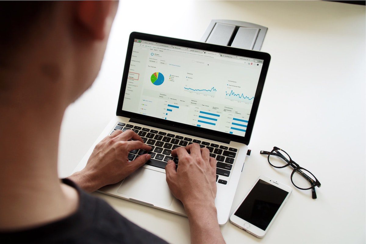 A man looking at data charts on his laptop screen with his fingers on the keyboard. Python for Data Science