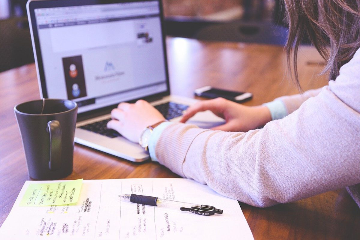 A woman typing on her laptop on a wooden table. Sales Projects