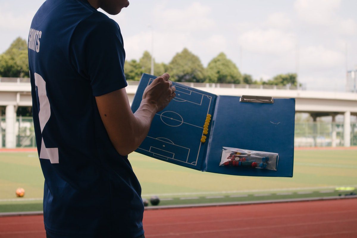 Man in a blue jersey holding a football tactics board. Sports Analytics Projects