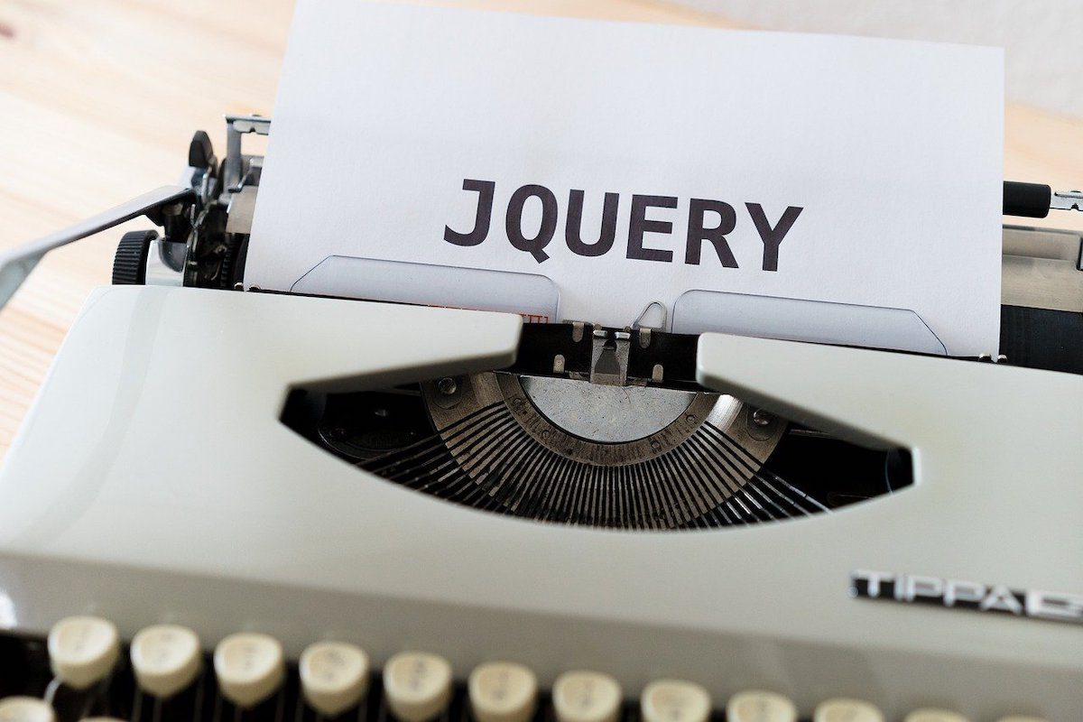 A white typewriter with a sheet of paper displaying the text “jQuery.”