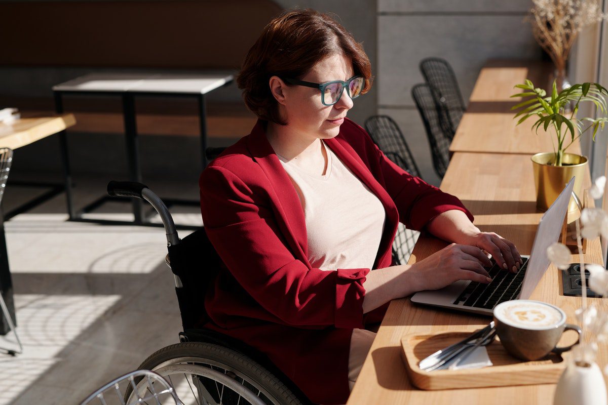 A woman sits at a cafe table as she works on something on her laptop. Online Ruby Courses