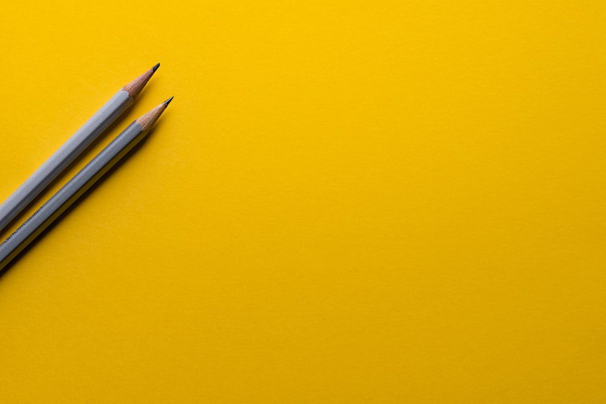 Two grey pencils on a yellow background. Online UI Design Courses