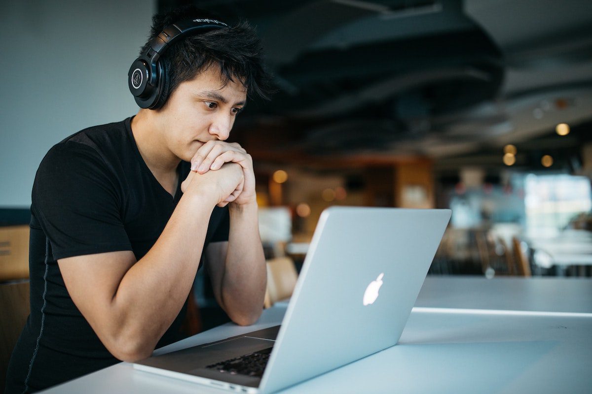 A man looking at a laptop screen with headphones on.