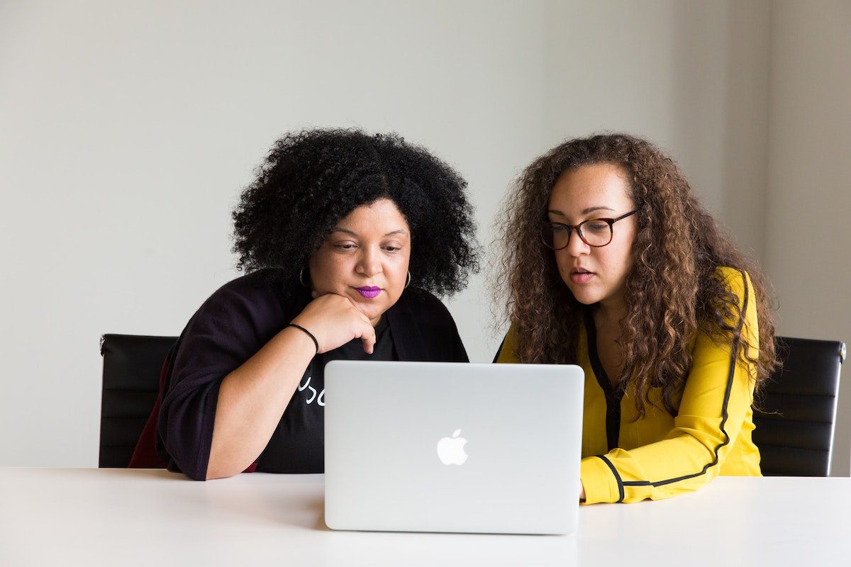 Two women sitting at a table looking at a laptop. How to Become a Staff Engineer